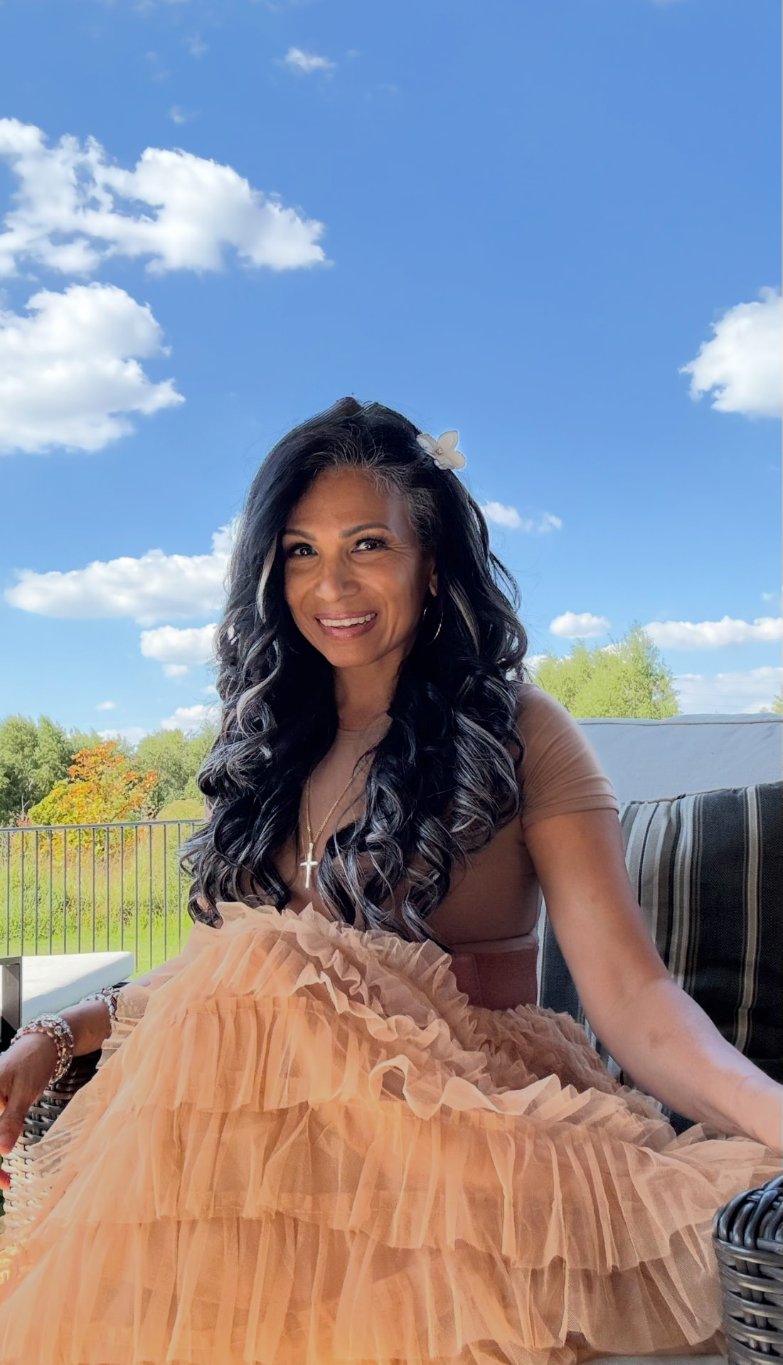 Portrait of the artist Karina Elena, smiling outdoors under a blue sky